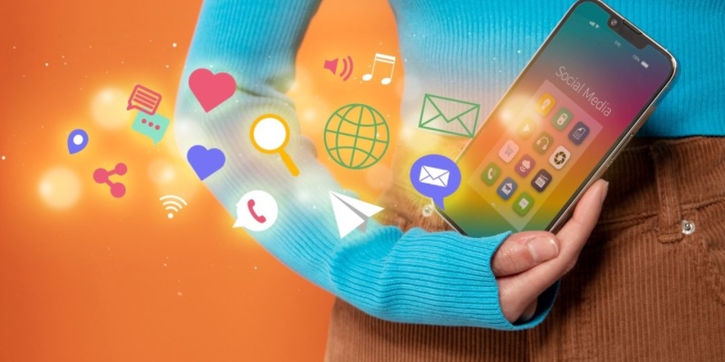 Pessoa a segurar um smartphone com aplicações de redes sociais, rodeado por ícones digitais que representam comunicação, interação e marketing digital.
