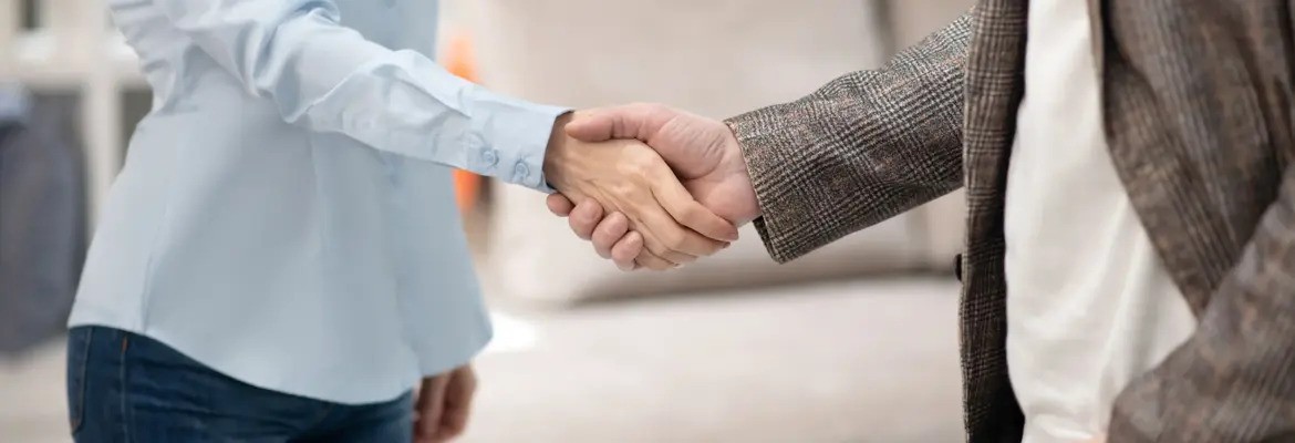 Pessoa a apertar a mão de outra, representando um acordo ou estabelecimento de relação profissional, possivelmente no contexto de negócio ou atendimento ao cliente.